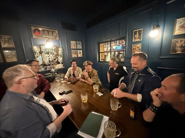 Members continue sharing card magic at a pub after the lecture